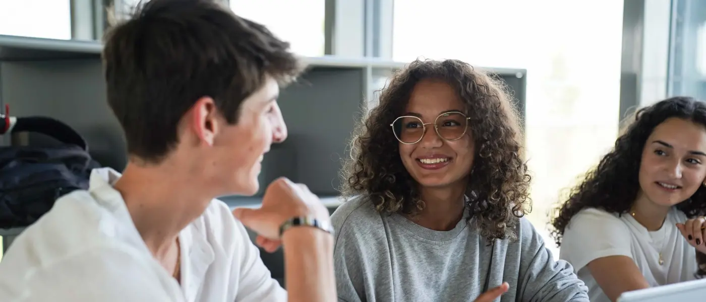 Happy H-FARM students engage on a project and write on the board