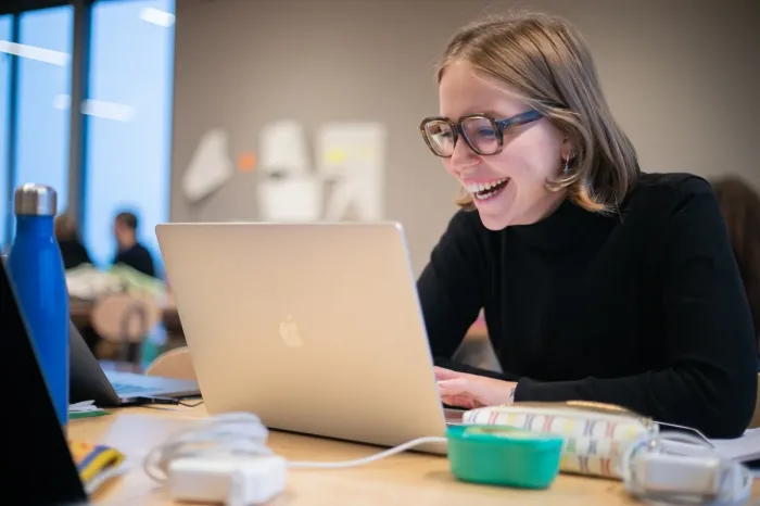 Studentessa sorridente al lavoro sul laptop in aula