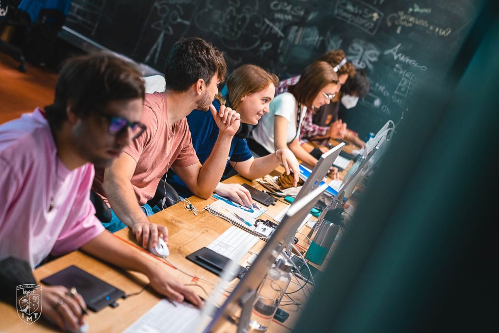 Studenti al lavoro alle postazioni davanti a una lavagna piena di schizzi