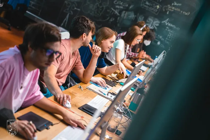 Studenti al lavoro alle postazioni davanti a una lavagna piena di schizzi