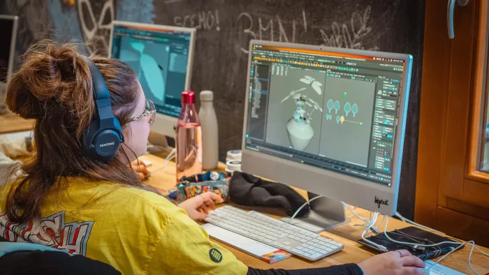Studentessa con cuffie lavora a un modello 3D sul monitor