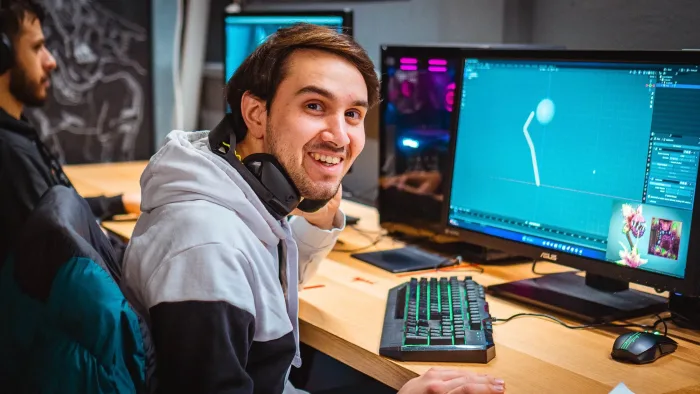 Studente sorridente alla sua postazione nel laboratorio di game design